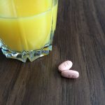 glass of orange juice next to 2 chemo pills