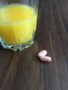 2 Xeloda pills next to a juice glass